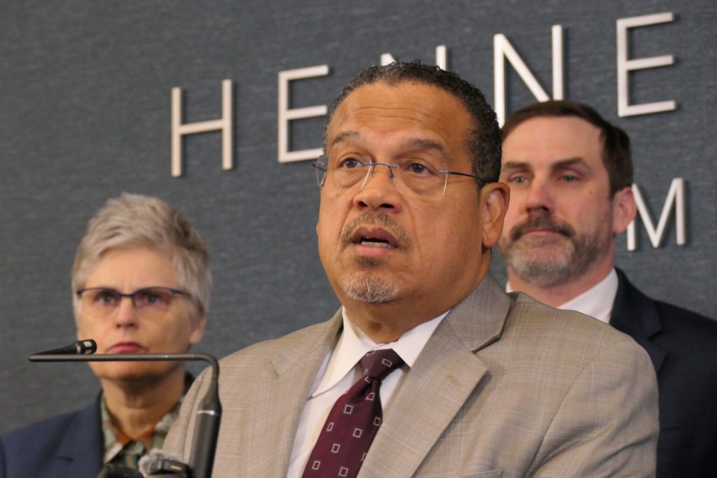 Minnesota Attorney General Keith Ellison speaks into a microphone alongside Mary Moriarty during a news conference.