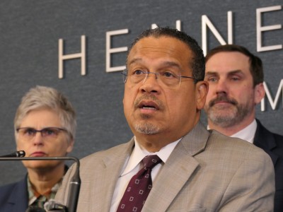 Minnesota Attorney General Keith Ellison speaks into a microphone alongside Mary Moriarty during a news conference.