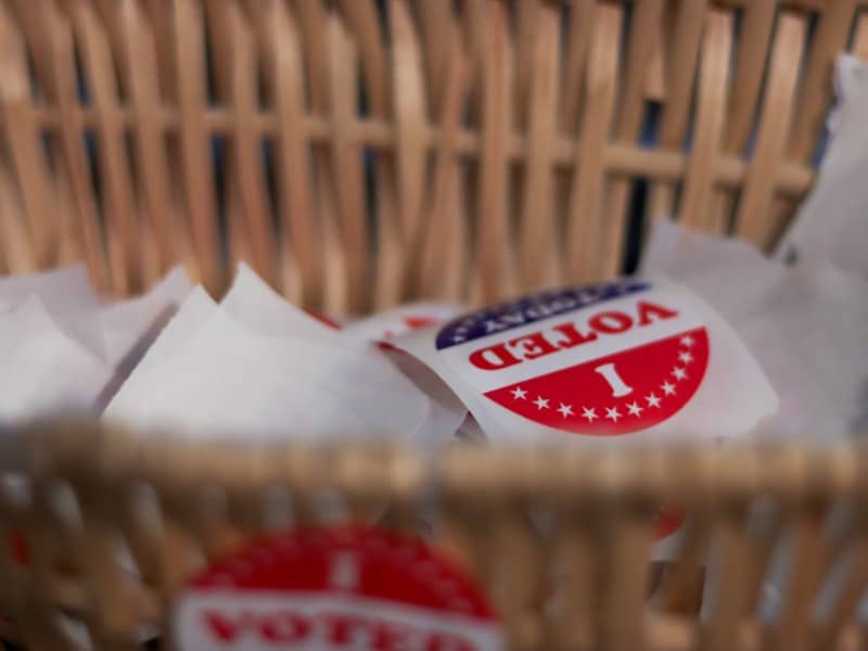 A close-up, shallow-focus shot of a wicker basket filled with red, white, and blue "I Voted Today" stickers.