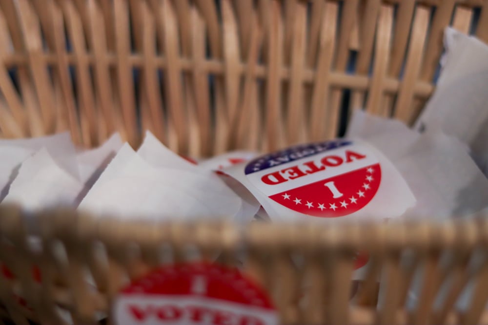 A close-up, shallow-focus shot of a wicker basket filled with red, white, and blue "I Voted Today" stickers.