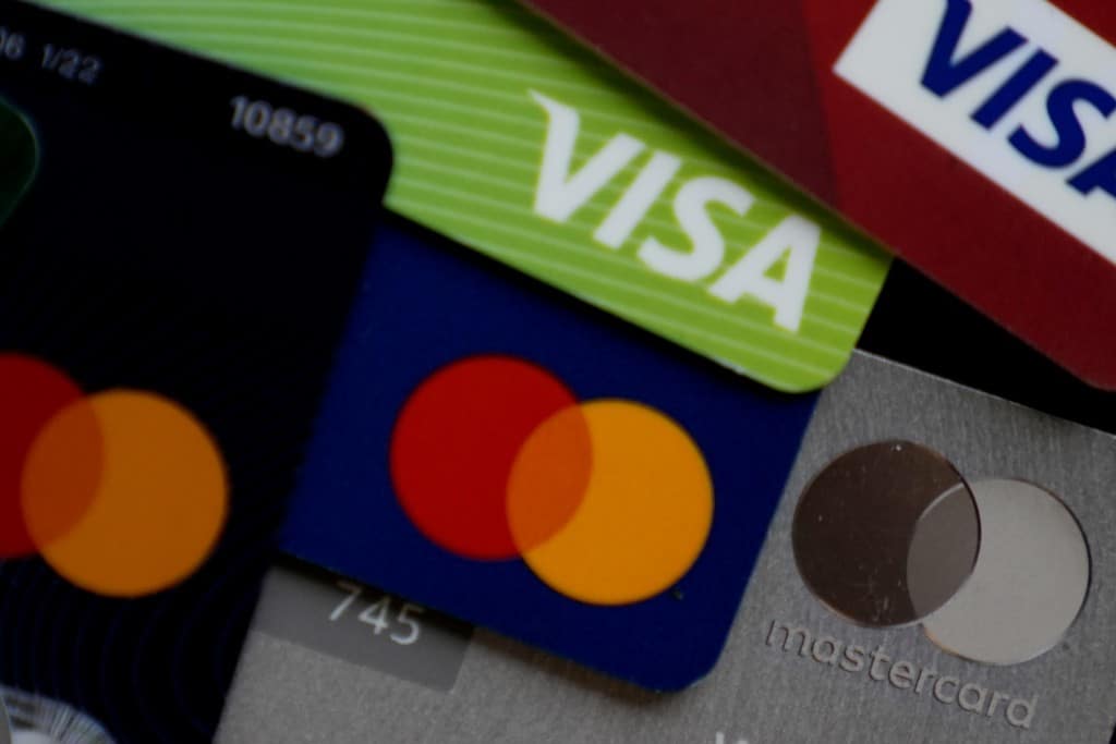A close-up, top-down shot of several overlapping credit cards showing the Visa and Mastercard logos.