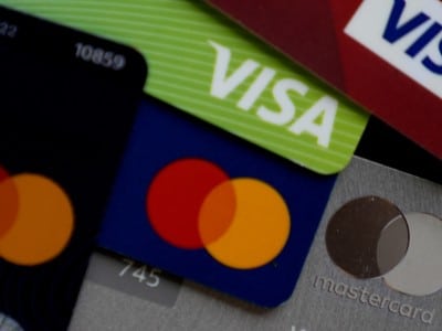 A close-up, top-down shot of several overlapping credit cards showing the Visa and Mastercard logos.