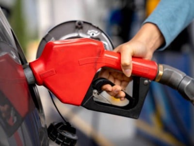 Close-up on a woman refueling her car at a gas station and holding a fuel pump - business concepts