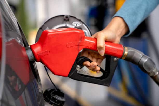 Close-up on a woman refueling her car at a gas station and holding a fuel pump - business concepts
