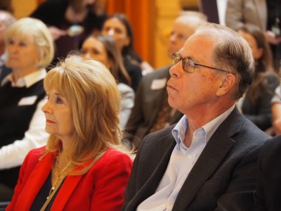 Indiana Governor Mike Braun wearing a dark blazer and sitting next to his wife, First Lady Maureen Braun in the Indiana statehouse.