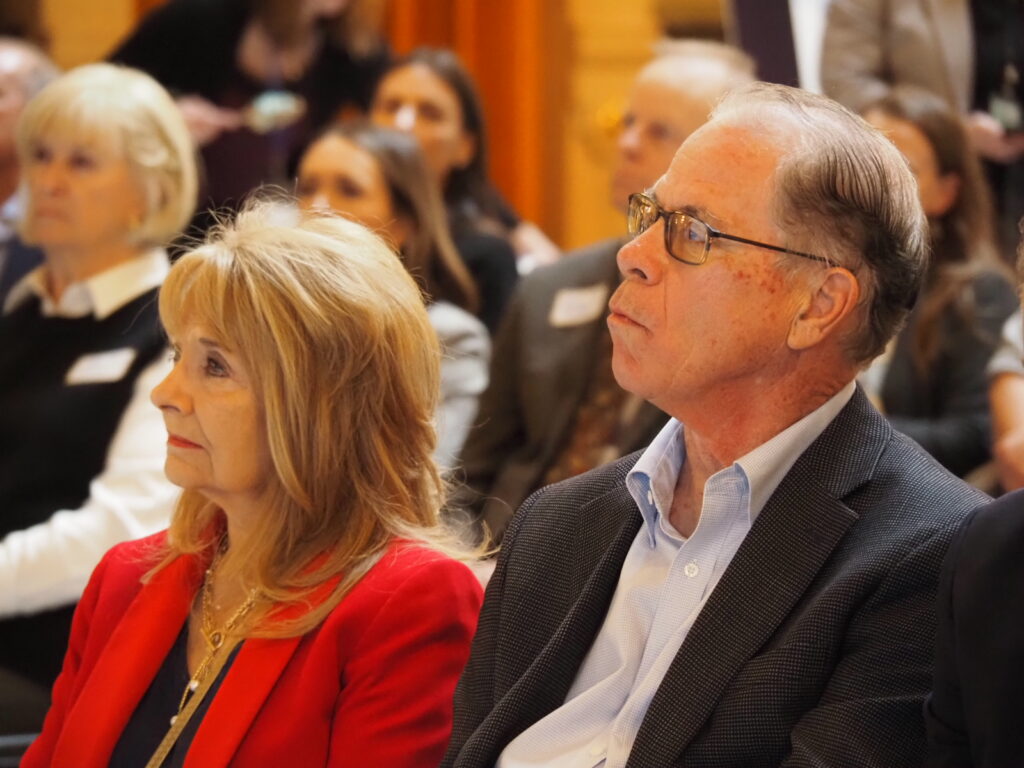 Indiana Governor Mike Braun wearing a dark blazer and sitting next to his wife, First Lady Maureen Braun in the Indiana statehouse.