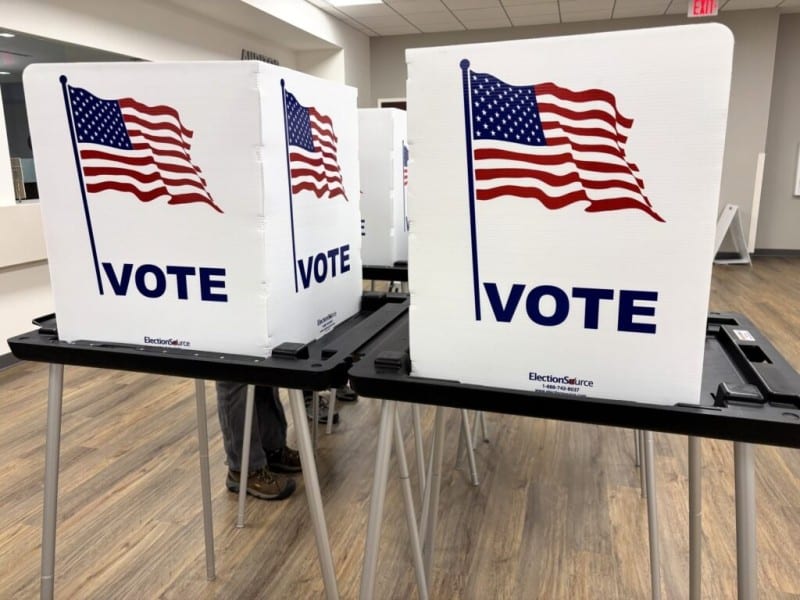 Voters standing inside a voting booth at a polling place.