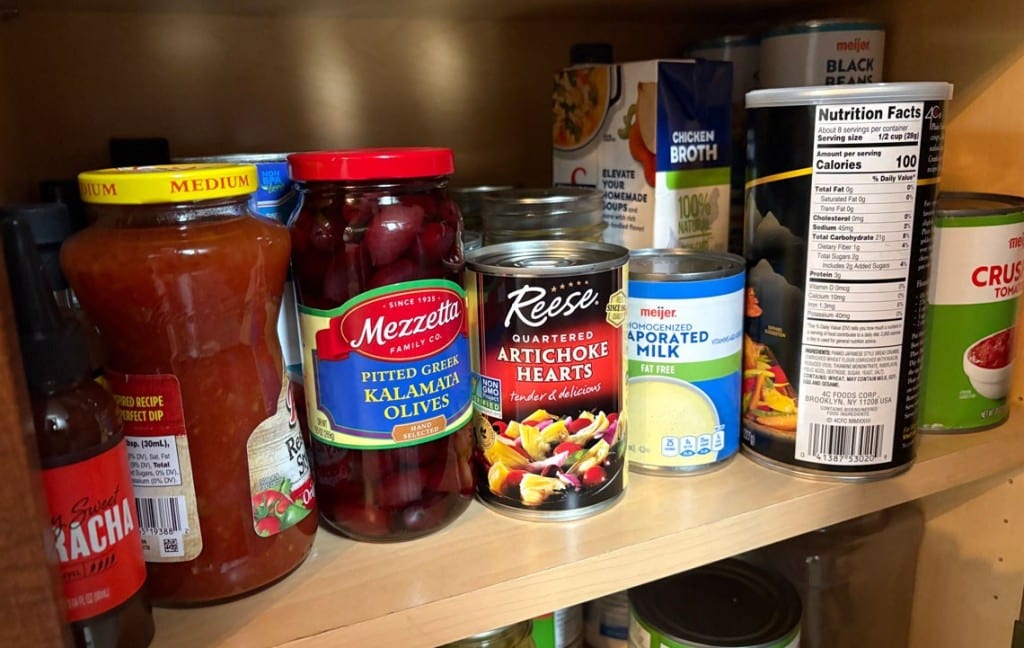 Canned goods on a shelf inside a pantry.
