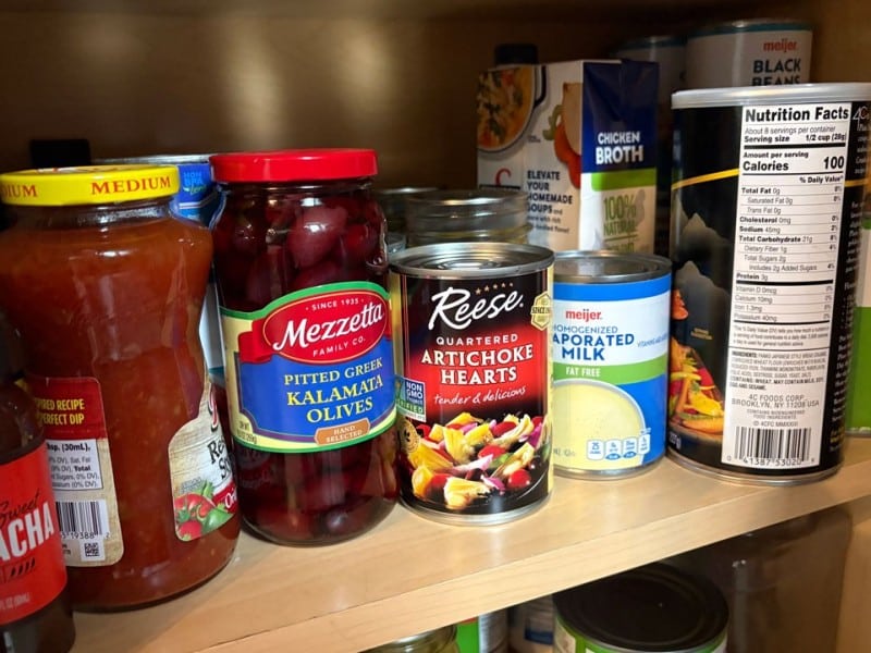 Canned goods on a shelf inside a pantry.