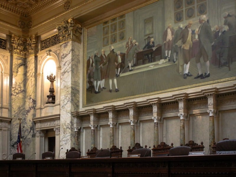 The empty judicial bench of the Wisconsin Supreme Court courtroom beneath a large historical mural.