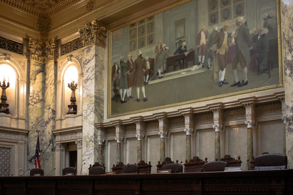 The empty judicial bench of the Wisconsin Supreme Court courtroom beneath a large historical mural.