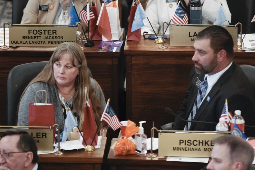 South Dakota State Senators Julie Frye-Mueller and Tom Pischke look to the left while seated at their desks on the Senate floor.