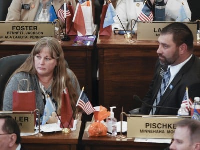 South Dakota State Senators Julie Frye-Mueller and Tom Pischke look to the left while seated at their desks on the Senate floor.