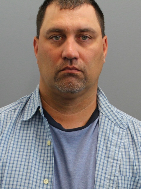 A booking photo of South Dakota State Senator Tom Pischke looking forward against a gray background.