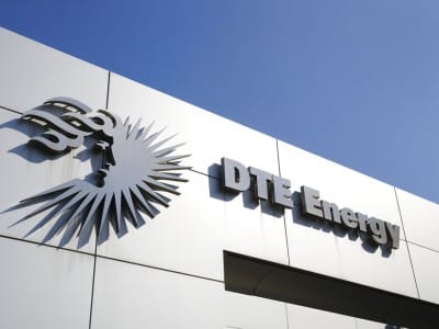 The DTE Energy logo and company name mounted on the side of a building against a clear blue sky.