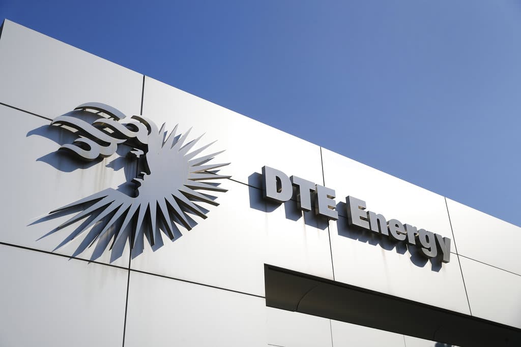 The DTE Energy logo and company name mounted on the side of a building against a clear blue sky.