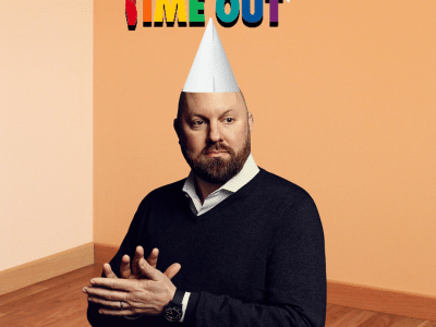 A photoshopped image of Marc Andreessen standing in a room corner, wearing a white dunce cap. Colorful text taped to the wall above him reads "TIME OUT".