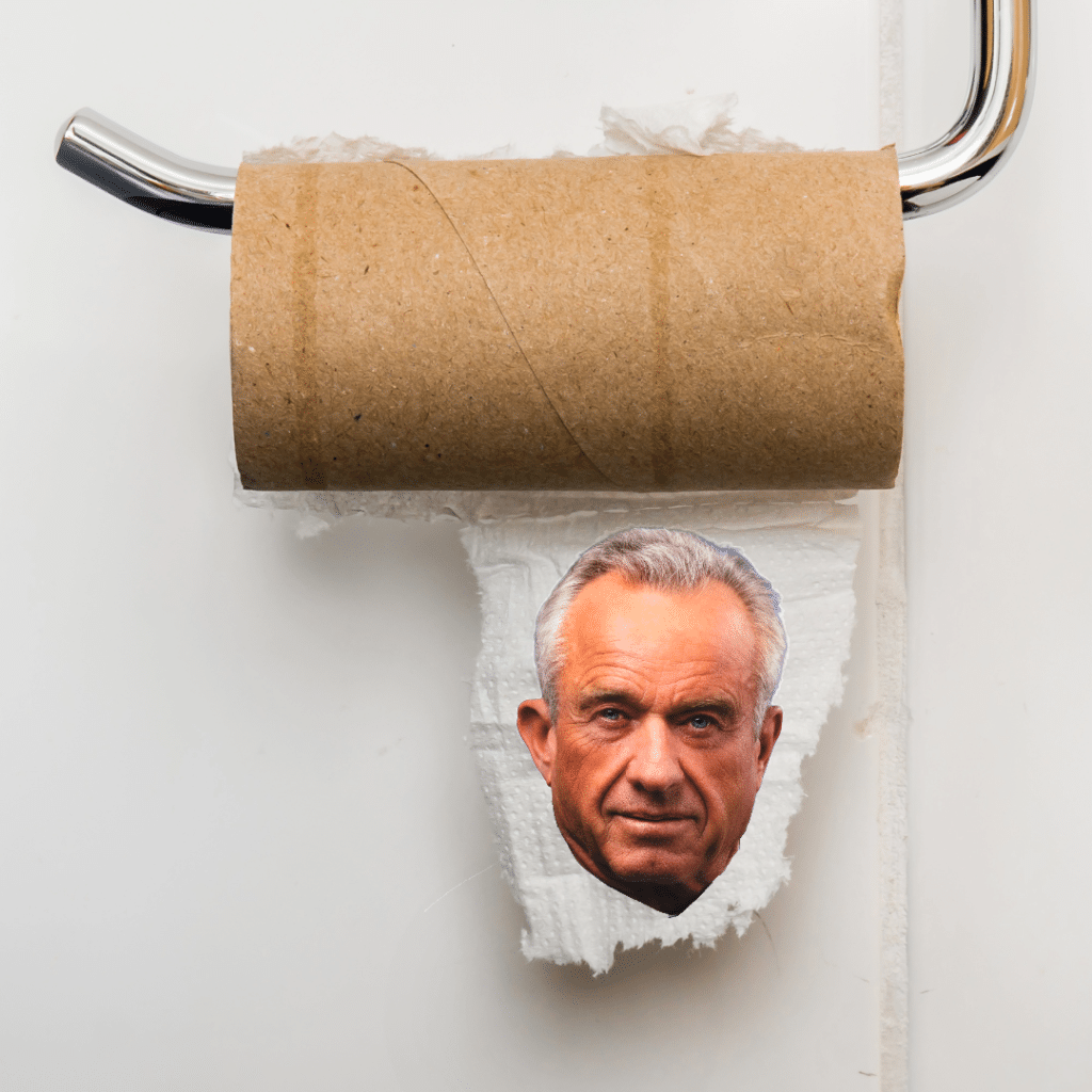 An empty, brown cardboard toilet paper roll on a chrome holder with a small piece of paper featuring Robert F. Kennedy Jr.'s face.