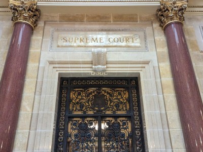 Ornate metal doors of the Wisconsin Supreme Court, flanked by marble columns under an engraved "SUPREME COURT" sign.