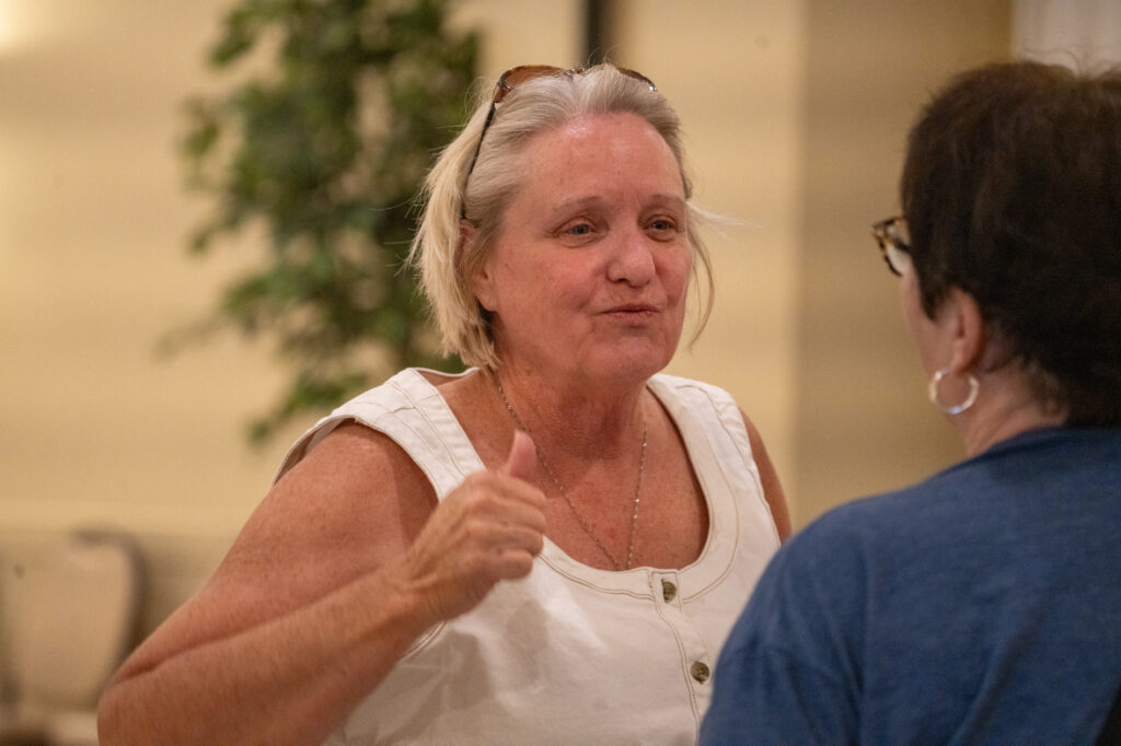 Cindy Burbank smiles and gives a thumbs-up while speaking to a person seen from behind