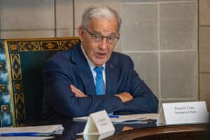 Nebraska Secretary of State Bob Evnen speaks from behind a desk with his arms folded during a meeting.