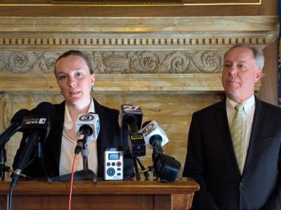 Greta Neubauer speaks into several microphones at a podium while Robin Vos stands beside her.