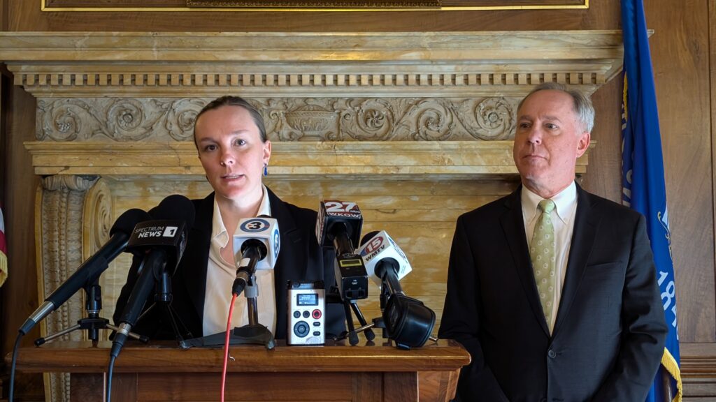 Greta Neubauer speaks into several microphones at a podium while Robin Vos stands beside her.