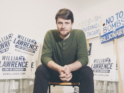 William Lawrence sits surrounded by campaign signs reading "William Lawrence for US Congress."