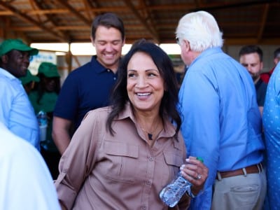 Lisa Demuth smiles as she mingles with supporters holding a water bottle in a barn's pavilion.