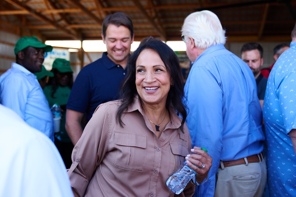 Lisa Demuth smiles as she mingles with supporters holding a water bottle in a barn's pavilion.