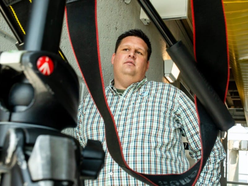 Nick Benson looks past a camera mounted on a tripod.