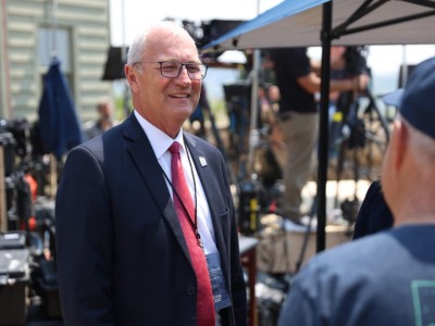 Kevin Cramer smiles in a suit while speaking to a reporter at an outdoor media event.