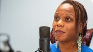 Rep. Brooklynne Mosley listens while seated near a studio microphone.