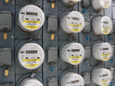 A wall filled with rows of round, digital electric utility meters labeled "LG&E."