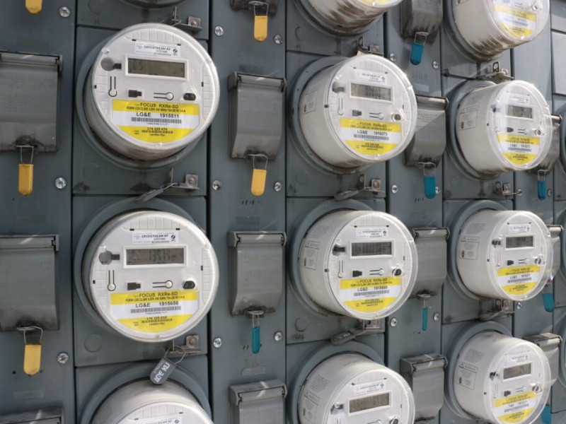 A wall filled with rows of round, digital electric utility meters labeled "LG&E."
