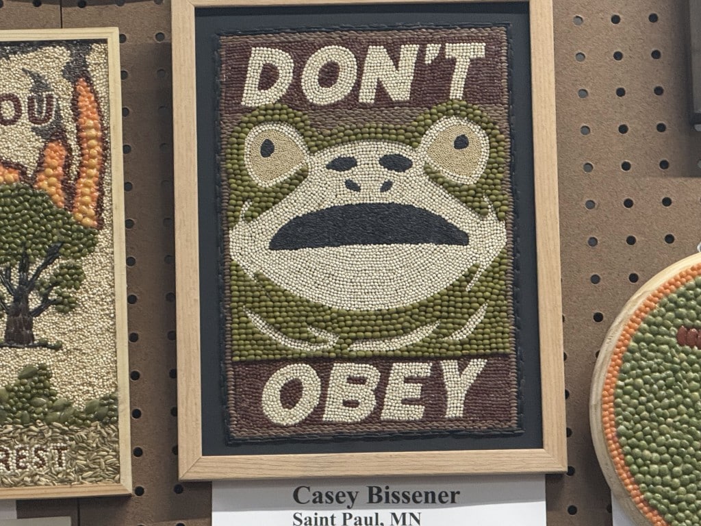 Seed art of a wide-eyed frog face framed by the text "DON'T OBEY."
