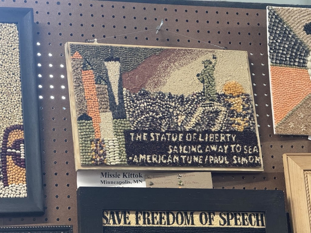 Seed art of the Statue of Liberty at sea with text "THE STATUE OF LIBERTY SAILING AWAY TO SEA - AMERICAN TUNE / PAUL SIMON."