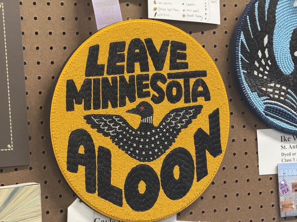 Circular seed art displaying a loon and the text "LEAVE MINNESOTA ALOON."