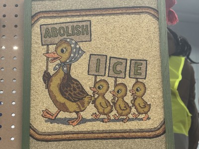 Seed art of a cartoon mother duck holding a sign that says "ABOLISH" and three ducklings holding signs that spell out "ICE"