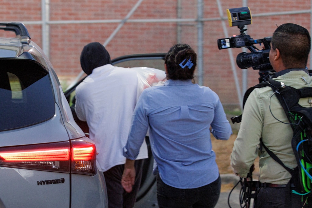 Christian Castro gets into a vehicle while carrying a plastic bag as reporters film him outside a detention center.