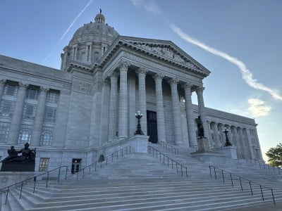 Broad stone steps lead up to the grand, columned facade and dome of the Missouri State Capitol.