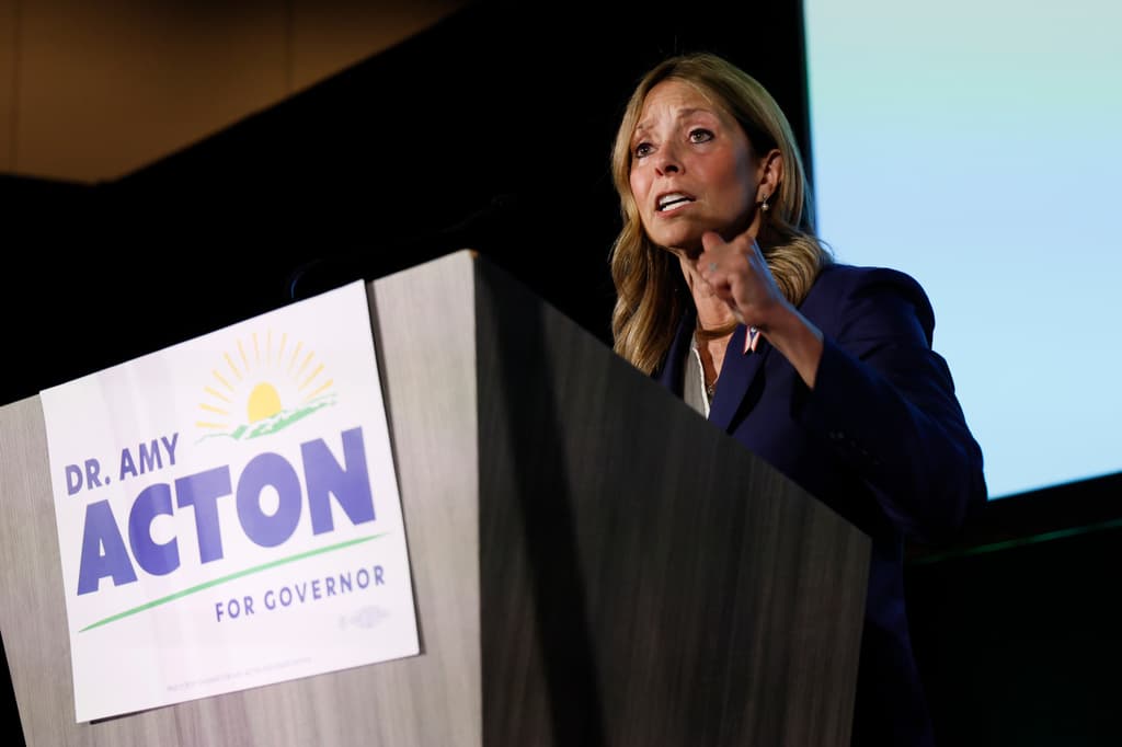 Dr. Amy Acton gestures while speaking at a podium bearing a sign that reads "DR. AMY ACTON FOR GOVERNOR."