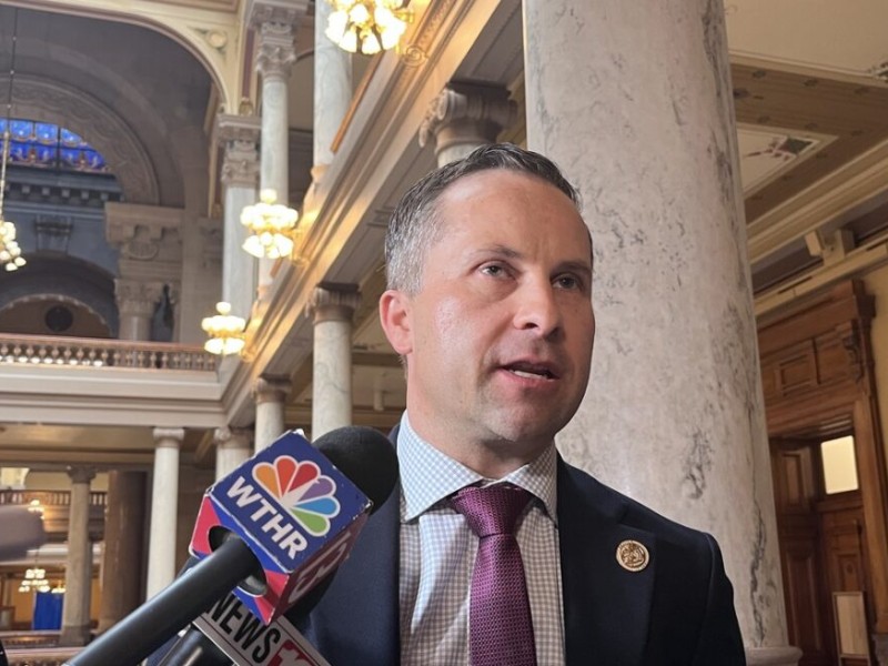 Indiana state Sen. Spencer Deery speaks into news microphones inside a grand hall with marble columns.