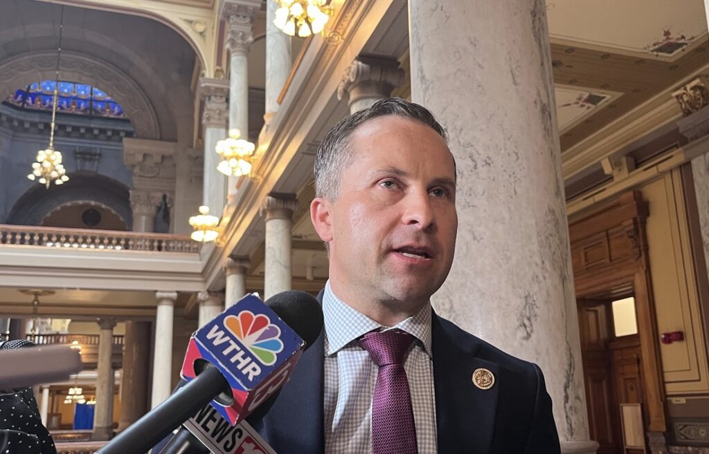 Indiana state Sen. Spencer Deery speaks into news microphones inside a grand hall with marble columns.