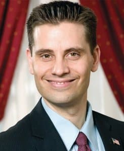 Wisconsin state Sen. Chris Kapenga smiles in a headshot portrait, wearing a suit, tie, and American flag lapel pin.