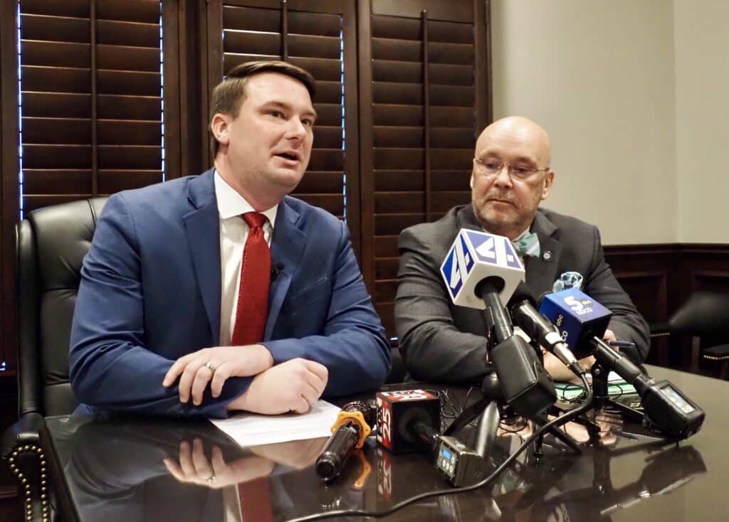 Kyle Hilbert and Mike Osburn sit at a table speaking into multiple press microphones.