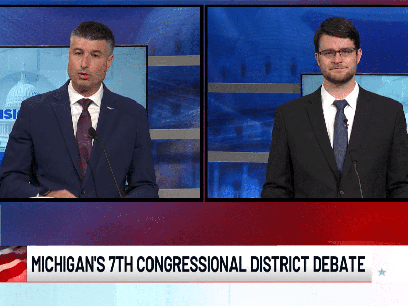 Tom Barrett and William Lawrence appear in a split-screen broadcast wearing suits beneath a "Michigan's 7th Congressional District Debate" banner.