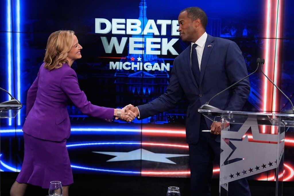 Democratic gubernatorial nominee and Michigan Secretary of State Jocelyn Benson, left, shakes hands with Rep. John James, R-Mich, Republican gubernatorial candidate at the start of a televised debate in Grand Rapids.