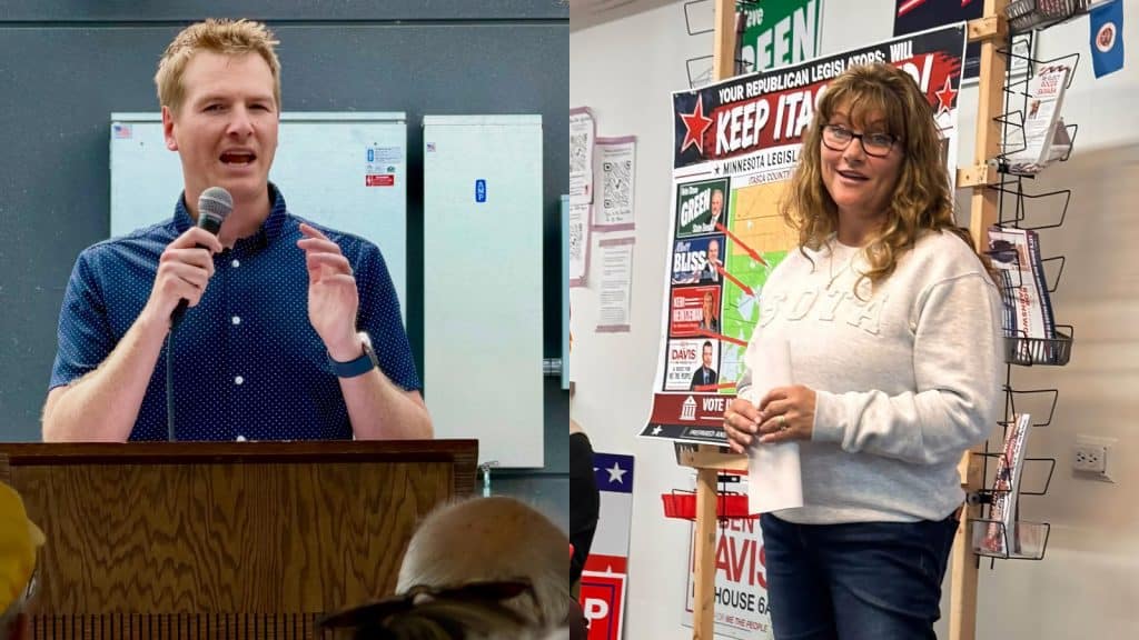 Grant Hauschild speaks at a wooden podium, and Andrea Zupancich stands next to campaign signs holding rolled papers.